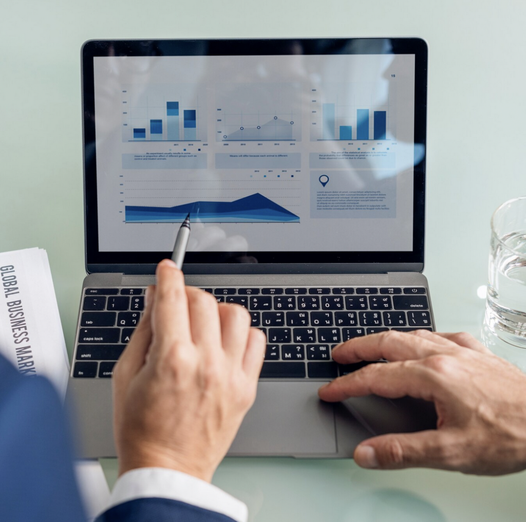 Hombre señalando gráficos en portátil mientras analiza datos empresariales