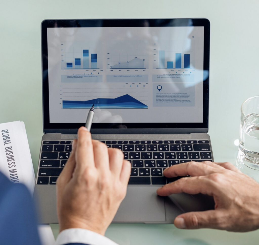 Persona analizando gráficos de datos en computadora portátil durante una reunión de negocios.